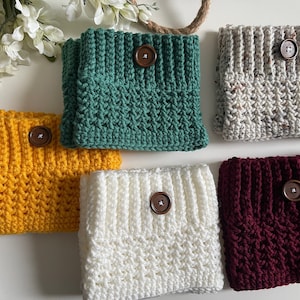 May include: Six crocheted leg warmers with wooden buttons. The leg warmers are in various colors, including green, gray, yellow, white, and burgundy.