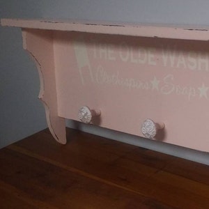 Shelf Painted Pale Pink with 3 knobs stenciled with "The Olde Washboard"