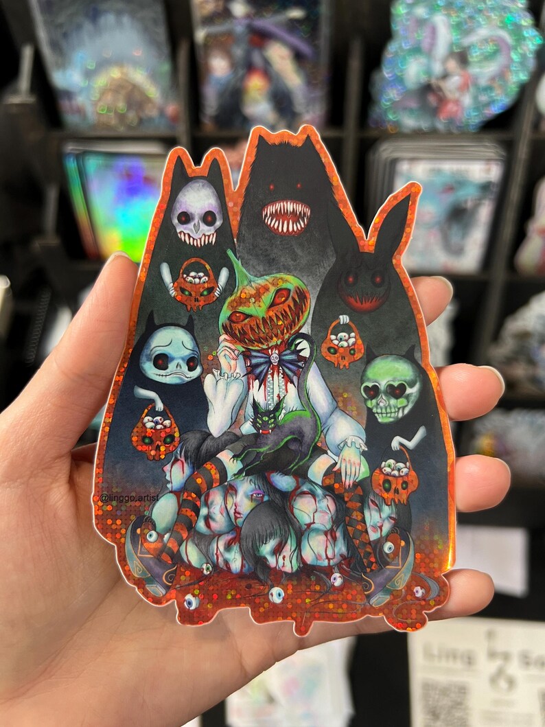 May include: A holographic sticker featuring a spooky Halloween-themed illustration. The artwork includes a pumpkin-headed figure, various monster silhouettes, and a pile of severed heads. The sticker has a glittery, iridescent finish.
