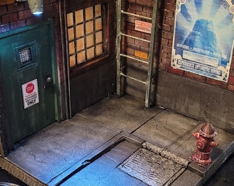 May include: A detailed miniature alleyway diorama featuring brick walls, a green door, and a metal ladder. The scene includes a red fire hydrant, a manhole cover, and a poster that reads "Enjoy the Atmosphere". Signs read "Arkham" and "Authorized Employees Only".