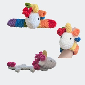 Puede incluir: Un conjunto de tres unicornios de peluche tejidos a ganchillo con hilo suave y grueso. Los unicornios tienen cabezas blancas, crines coloridas en tonos rojo, amarillo, verde, azul y naranja, y cuerpos a rayas de arcoíris. Uno es una pulsera.