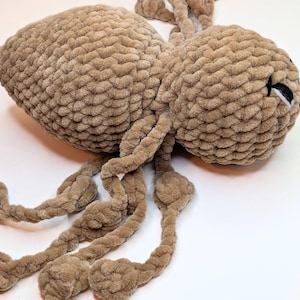 Side view of a crochet plush spider fidget toy. The side view highlights how long the legs are for pulling back and forth.