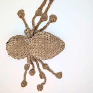 Top down view of a light brown crocheted spider. There are eight long legs that can be pulled back and forth the create a quiet fidget toy.