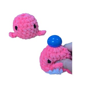 Peut inclure: Jouet en peluche de baleine rose en crochet avec une boule bleue sur le dessus. La baleine est douce et moelleuse et peut être pressée.