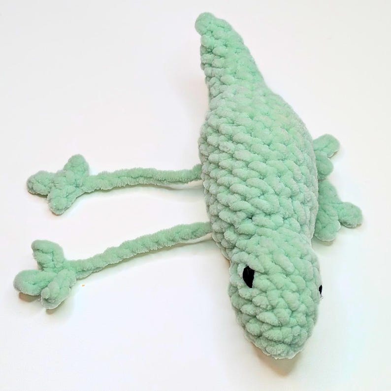 A crochet lizard with elongated legs showing they can be pulled back and forth to create a fidget toy.