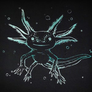 Könnte beinhalten: Ein blaugrüner Axolotl mit freundlichem Gesichtsausdruck, weiß umrandet, vor schwarzem Hintergrund. Der Axolotl ist von kleinen weißen Kreisen umgeben, die wie Blasen aussehen.