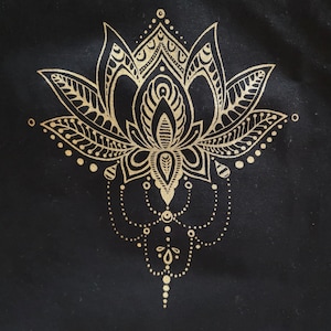 Könnte beinhalten: Ein goldfarbenes Lotusblumen-Mandala-Design auf einem schwarzen Stoffhintergrund.