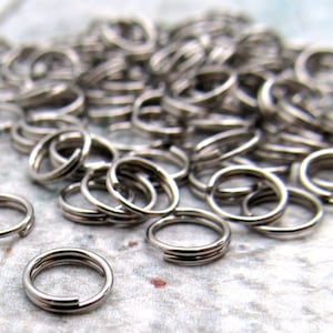 May include: A pile of silver jump rings, a type of metal ring used in jewelry making.