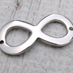 Puede incluir: Un amuleto de plata en forma de símbolo de infinito con dos agujeros para sujetarlo a joyas u otras manualidades.