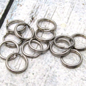 May include: A close-up of a pile of silver key rings. The key rings are all the same size and are made of metal.