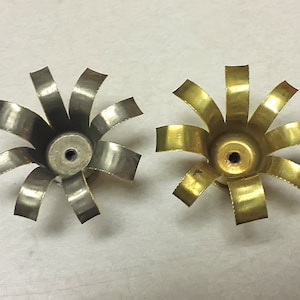 May include: Two metal flower-shaped objects with eight petals each. One is silver and the other is gold.