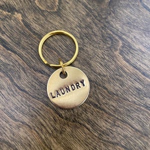 May include: A gold-colored key chain with a round tag that says "LAUNDRY" in black lettering.