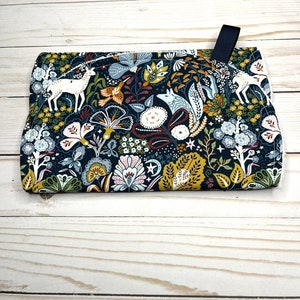 May include: A dark blue fabric pot holder with a whimsical floral pattern featuring white deer, foxes, and birds. The pattern also includes stars, leaves, and flowers in shades of yellow, green, pink, and red.