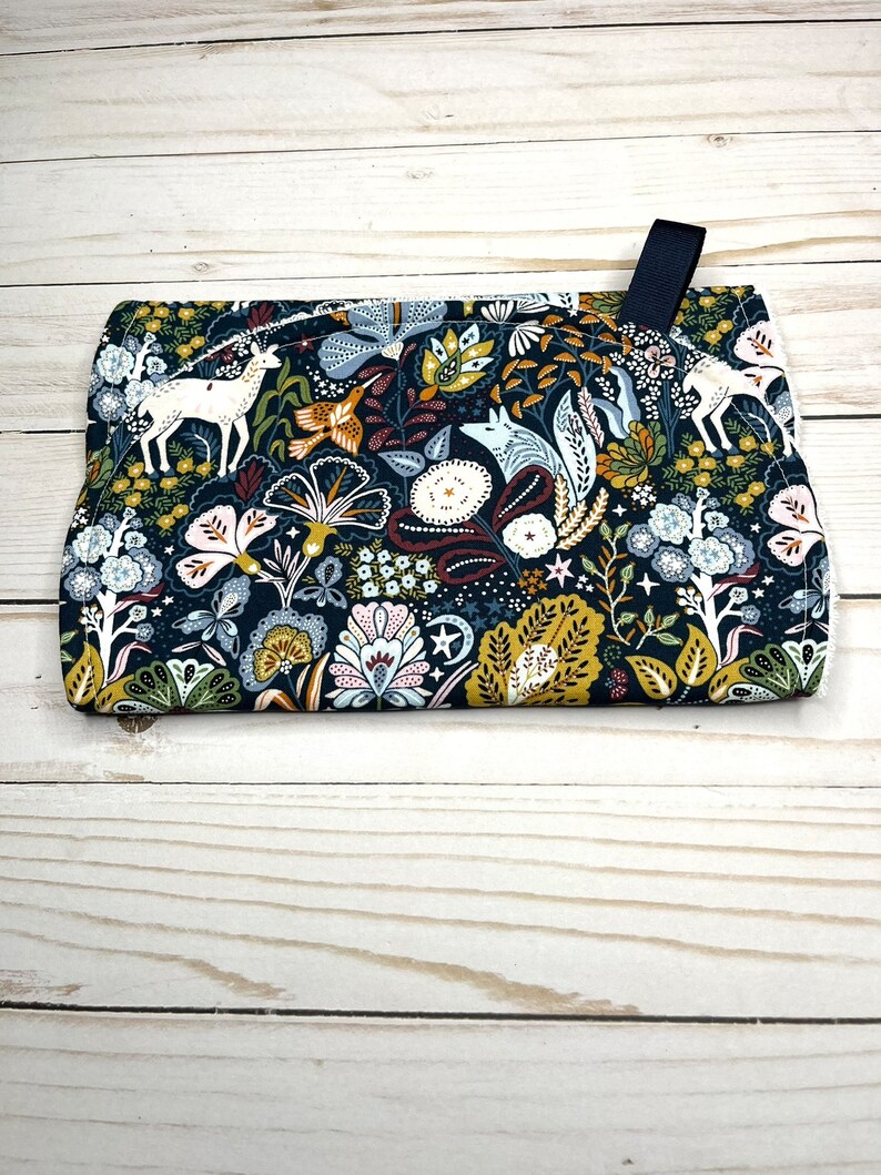 May include: A dark blue fabric pot holder with a whimsical floral pattern featuring white deer, foxes, and birds. The pattern also includes stars, leaves, and flowers in shades of yellow, green, pink, and red.
