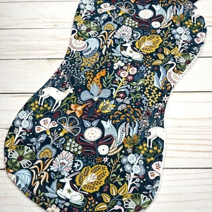 May include: A dark blue pot holder with a white, yellow, and green floral pattern featuring deer, birds, and other woodland creatures.