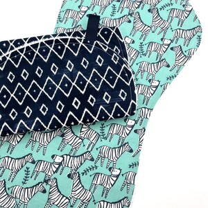 May include: Two pot holders, one with a black and white geometric pattern and the other with a green background and black and white zebra print.