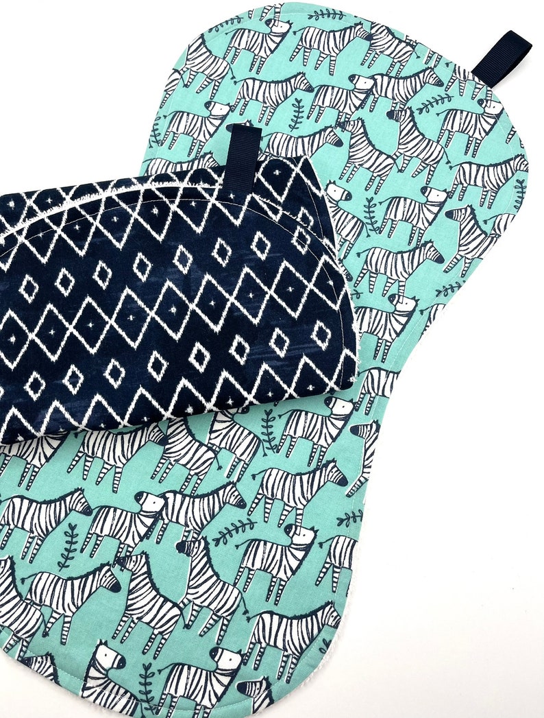 May include: Two pot holders, one with a black and white geometric pattern and the other with a green background and black and white zebra print.