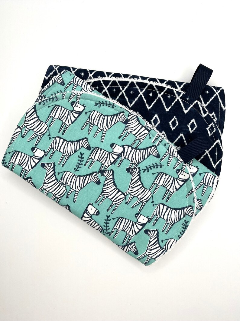 May include: Two kitchen towels, one with a black and white geometric pattern and the other with a green background and a black and white zebra print.