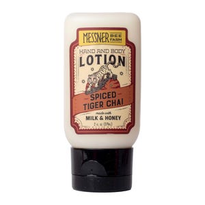 May include: A white plastic squeeze bottle of Messner Bee Farm hand and body lotion. The label features a tiger illustration, the text Spiced Tiger Chai, and states it is made with milk and honey, with a volume of 2 fl oz (59 ml) and a black cap.