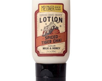 May include: A white plastic squeeze bottle of Messner Bee Farm hand and body lotion. The label features a tiger illustration, the text Spiced Tiger Chai, and states it is made with milk and honey, with a volume of 2 fl oz (59 ml) and a black cap.