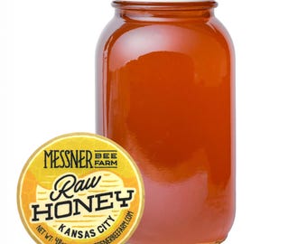 Puede incluir: Un tarro de vidrio transparente lleno de miel cruda, con tapa dorada. A la izquierda, una etiqueta redonda amarilla con el texto "Messner Bee Farm Raw Honey Kansas City". El tarro contiene 1360g de miel.