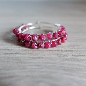 May include: A pair of silver hoop earrings with a double row of pink ruby gemstone beads.