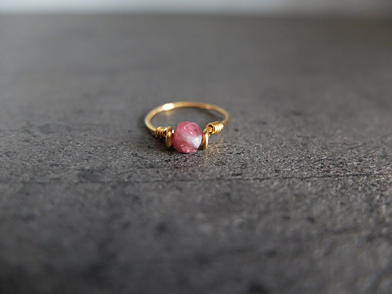 K&ouml;nnte beinhalten: Ein zarter Goldring mit einem rosafarbenen und wei&szlig;en Edelstein, der in Draht gewickelt ist.