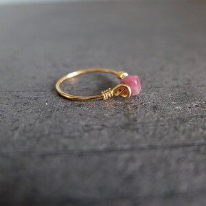 K&ouml;nnte beinhalten: Ein goldener Ring mit einem rosafarbenen Edelstein, der in Draht gewickelt ist.