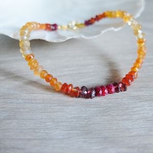 Peut inclure: Un collier de pierres précieuses graduées avec des perles orange, rouges et rubis. Le collier est fait de pierres précieuses naturelles et est enfilé sur une chaîne en or.