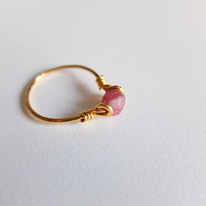 K&ouml;nnte beinhalten: Ein goldener Ring mit einem rosafarbenen Edelstein, der in Draht gewickelt ist.