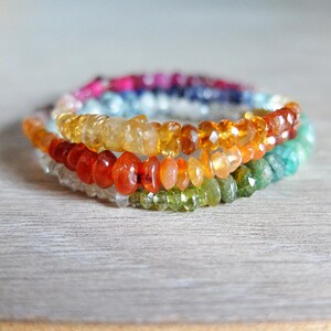 Puede incluir: Un brazalete de piedras preciosas multicolores con un arcoíris de colores, incluyendo rojo, naranja, amarillo, verde, azul y morado.