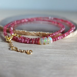 May include: A delicate gold chain necklace with pink gemstone beads and three opal beads.