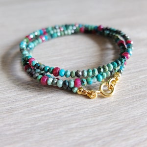 Peut inclure: Un bracelet enroulé composé de petites perles facettées de couleur turquoise, rouge rubis et gris foncé. Le bracelet est doté d'un fermoir doré. Les perles sont enfilées pour créer un effet superposé, idéal pour ajouter une touche de couleur.
