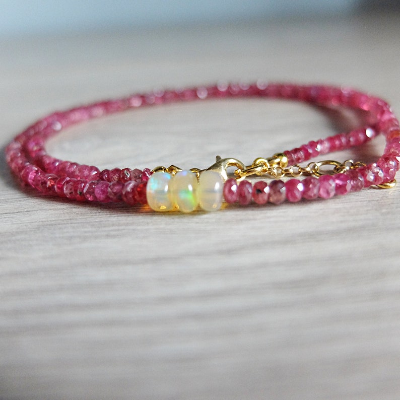 May include: A delicate gold chain necklace with a double strand of pink tourmaline beads and three opal beads in the center.
