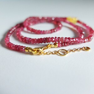 May include: A delicate pink gemstone necklace with a gold clasp and chain. The necklace is made of small, faceted gemstones and is perfect for layering.