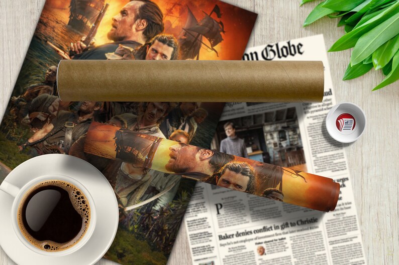 May include: A rolled up poster depicting a group of people in a pirate-themed scene. The poster is on a wooden table with a cup of coffee and a newspaper.