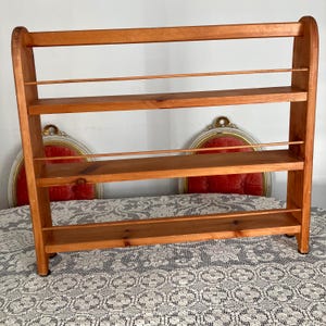 May include: A wooden shelf unit with three shelves. The shelf is made of natural wood and has a rustic look. It is perfect for displaying small items or organizing a kitchen.
