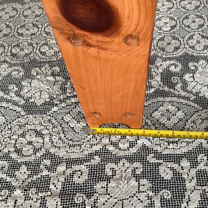 Puede incluir: Primer plano de la parte inferior de una pata de silla de madera con cuatro peque&ntilde;os pies redondos de pl&aacute;stico transparente. La pata de la silla es de color marr&oacute;n claro y tiene una veta de madera natural. Una cinta m&eacute;trica amarilla es visible en la parte inferior de la imagen.