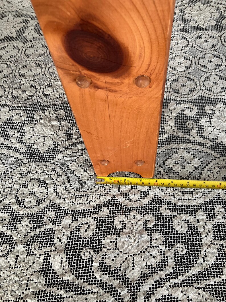 Puede incluir: Primer plano de la parte inferior de una pata de silla de madera con cuatro peque&ntilde;os pies redondos de pl&aacute;stico transparente. La pata de la silla es de color marr&oacute;n claro y tiene una veta de madera natural. Una cinta m&eacute;trica amarilla es visible en la parte inferior de la imagen.