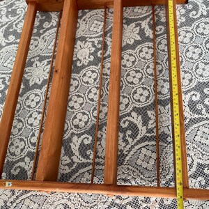 Puede incluir: Una estanter&iacute;a de madera con tres compartimentos y una parte superior decorativa. La estanter&iacute;a est&aacute; hecha de madera natural y tiene un aspecto r&uacute;stico.