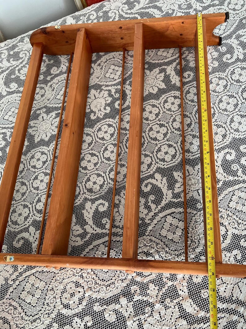 Puede incluir: Una estanter&iacute;a de madera con tres compartimentos y una parte superior decorativa. La estanter&iacute;a est&aacute; hecha de madera natural y tiene un aspecto r&uacute;stico.