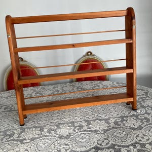Puede incluir: Una estanter&iacute;a de pared de madera con cuatro estantes y una rejilla de alambre en cada estante. La estanter&iacute;a est&aacute; hecha de madera natural y tiene un aspecto r&uacute;stico.