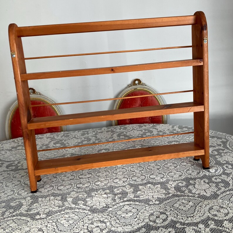 Puede incluir: Una estanter&iacute;a de pared de madera con cuatro estantes y una rejilla de alambre en cada estante. La estanter&iacute;a est&aacute; hecha de madera natural y tiene un aspecto r&uacute;stico.