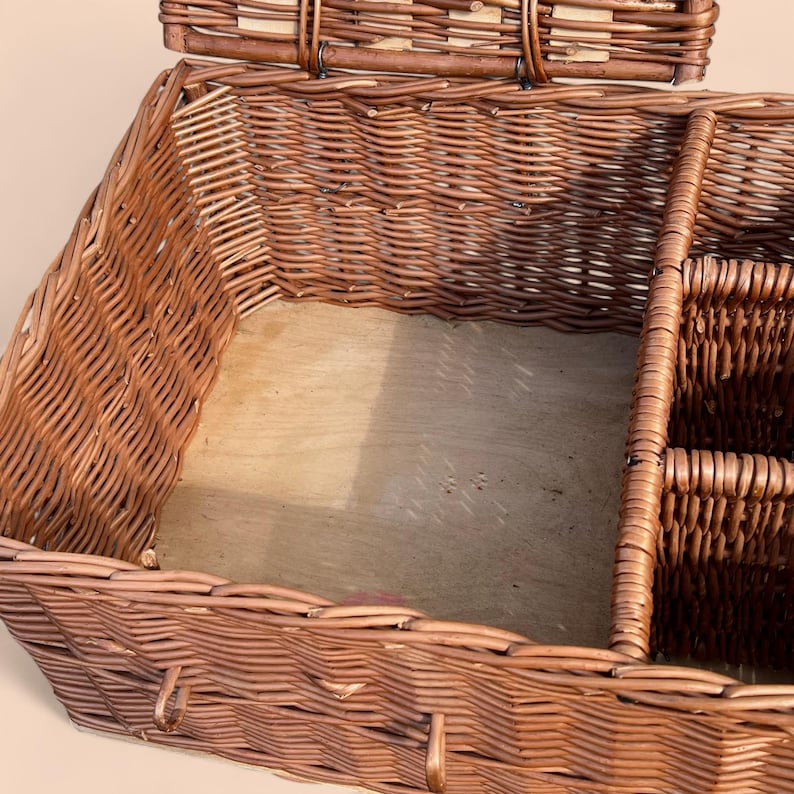 May include: A brown wicker basket with a hinged lid and a wooden base. The basket has a rectangular shape with a woven design and metal clasps. It features interior compartments for organization.