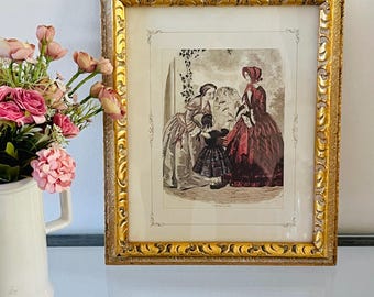 Könnte beinhalten: Ein antiker gerahmter Druck von drei Frauen in einer Gartenlandschaft. Die Frauen tragen Kleidung aus dem 19. Jahrhundert und sind in einer formellen Pose dargestellt. Der Druck ist in einem goldenen Rahmen mit verzierten Details.