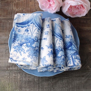 May include: A white ceramic mug with a black handle and the text "But First, Coffee" in a bold, black font. The mug is set against a blurred background, suggesting a cozy setting.