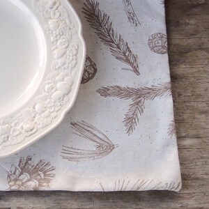 May include: A white ceramic plate with a raised floral design sits on a beige placemat with a brown pine needle pattern.
