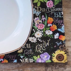 May include: A black placemat with a floral design and inspirational text. The text includes "Don't Worry Be Happy", "You Can Grow", and "I've Got This".