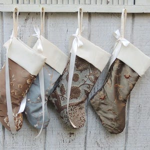 May include: Four decorative Christmas stockings with white cuffs and brown, blue, and gold patterned fabric.