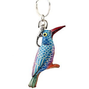 May include: A colorful leather bird keychain with a silver key ring. The bird is blue, green, purple, and red with a yellow eye.